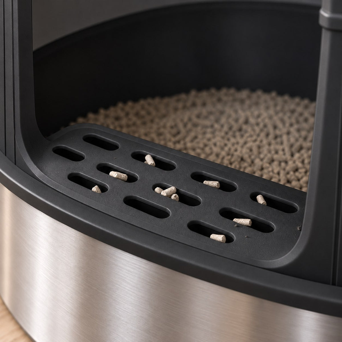 Close-up of the black slotted front step with litter pellets caught in the slots